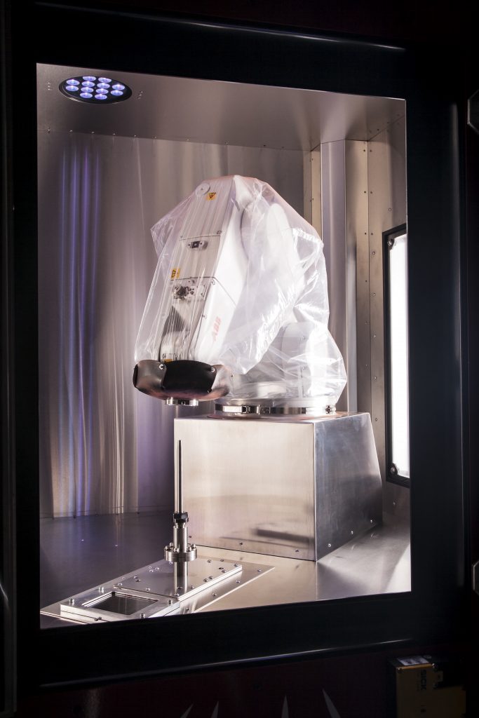 Inside the build chamber of the LightSPEE3D 3D-printer. The rocket nozzle that feeds supersonic-speed metal powders stands vertically at the bottom. The build plate moves in 6-axes as attached to a robotic arm. If a larger part is required, a larger robot can be used. (Image courtesy SPEE3D)